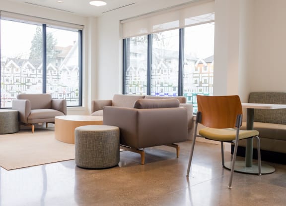 a living room with couches chairs and tables and windows