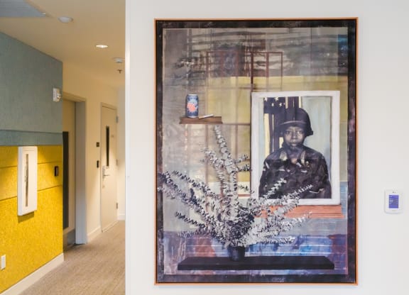 a painting on a wall in a hallway with a vase of flowers