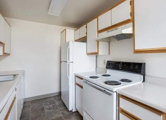 A kitchen with white appliances and wooden cabinets.