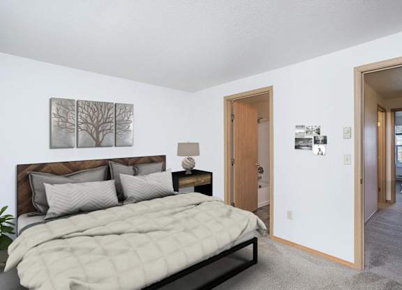 A bedroom with a bed, nightstand, and a painting on the wall.