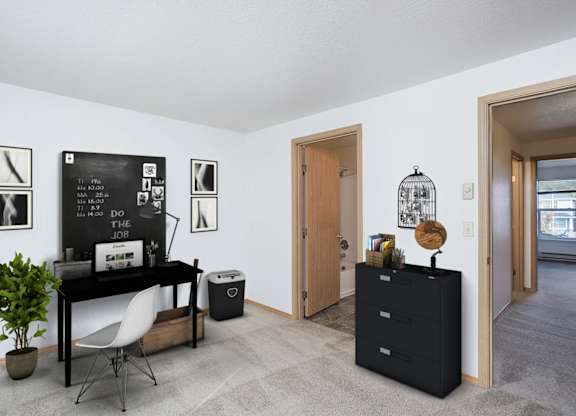 A black desk with a white chair and a black cabinet with a plant on top.