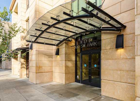 The entrance to a building with a glass canopy and a black door.