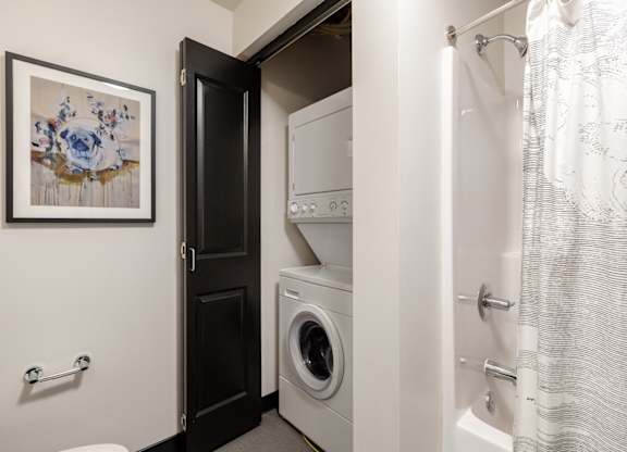 A bathroom with a washing machine and a shower.