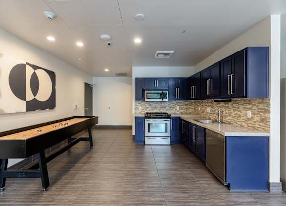 A modern kitchen with blue cabinets and a pool table.