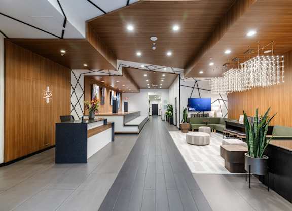 A modern office lobby with a long wooden hallway and a reception desk on the left.