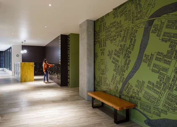 A person is standing in a hallway with a green wall map.