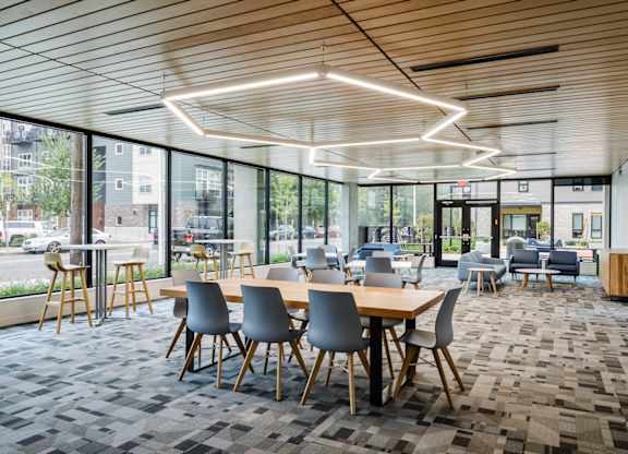 A modern dining area with wooden tables and grey chairs.