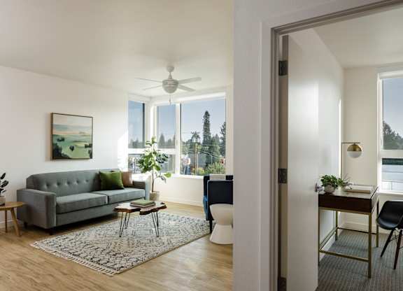 A living room with a grey couch and a painting on the wall.