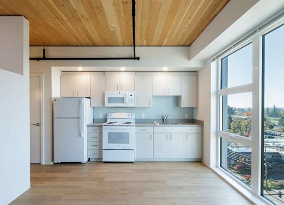 A modern kitchen with white appliances and wooden floors.