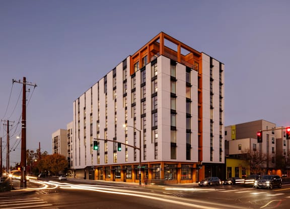 A modern building with a red and white facade stands tall on a street corner.