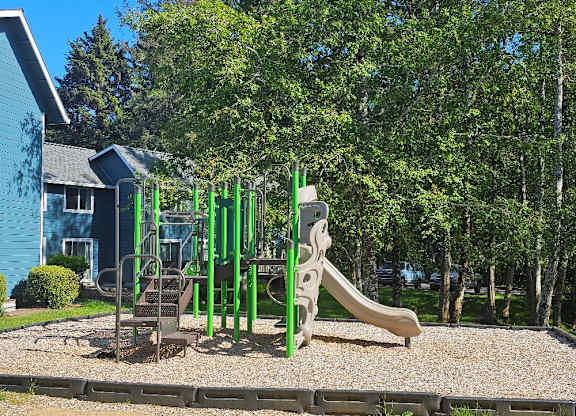 A playground with a green slide and a brown slide.