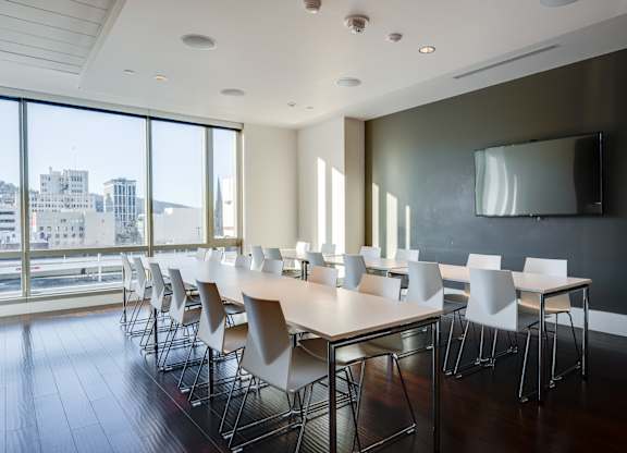 A conference room with a long table and chairs with a city view through the windows.