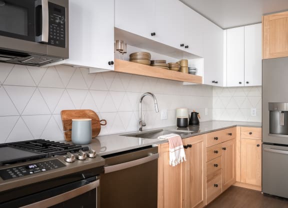 a kitchen with stainless steel appliances and wooden cabinets at Slabtown Square Apartments, Portland ,Oregon, 97209