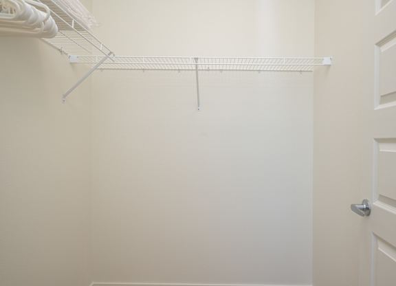 A white closet with a door and a shelf.