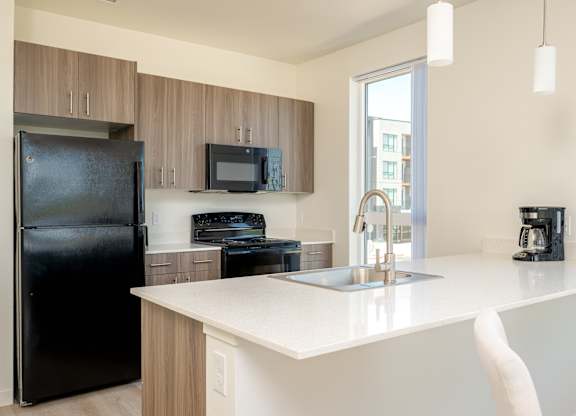 A black refrigerator is in a kitchen with a white counter.