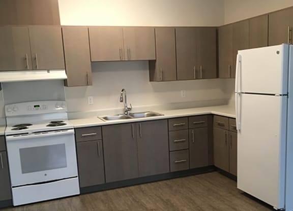 an empty kitchen with a stove refrigerator and sink