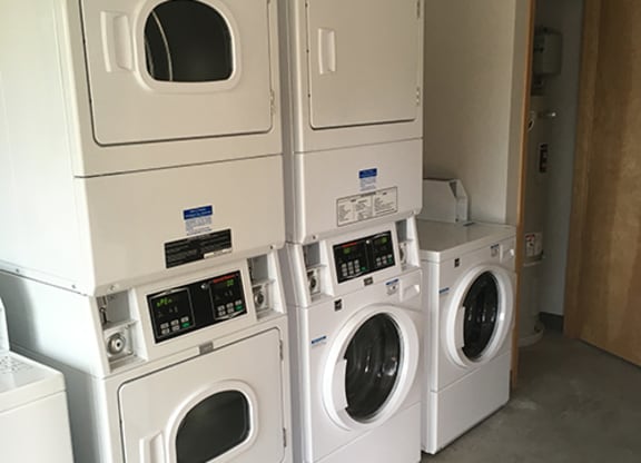 a bunch of washers and dryers in a laundry room