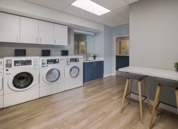 a laundry room with washers and dryers and a table with stools