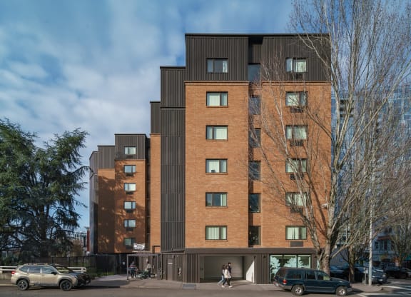 a tall brick building with a black facade and people walking in front of it