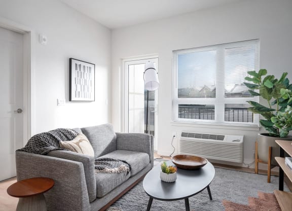 a small living room with a gray couch and a round coffee table