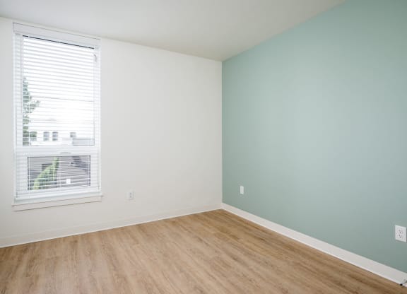 an empty room with a window and wooden floors