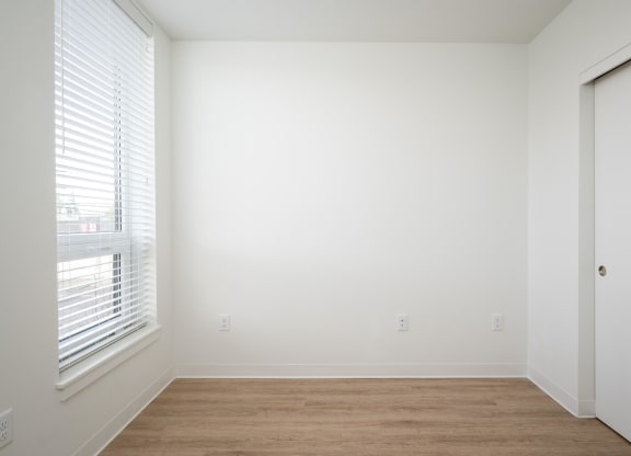 a bedroom with a large window and a wooden floor