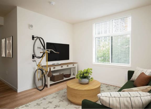 a living room with a green couch and a kitchen with a fan and a window