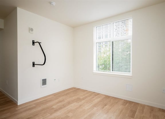 an empty room with a large window and wooden floors