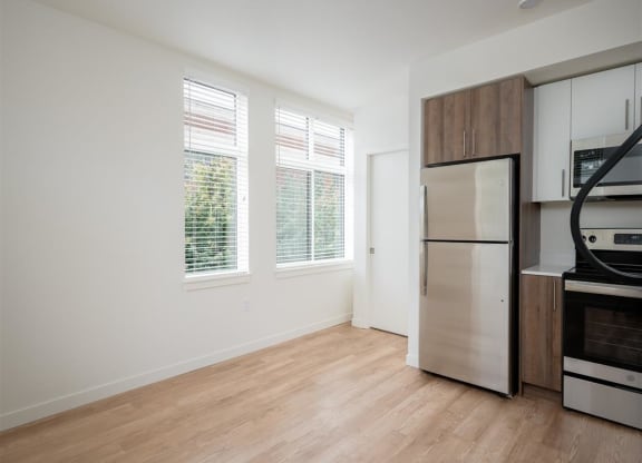 an empty kitchen with a stainless steel refrigerator and a window