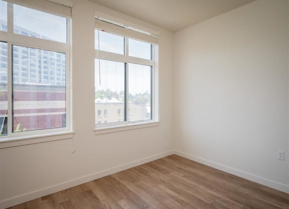an empty room with three windows and a wooden floor