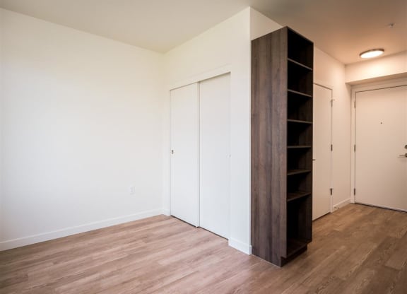 a bedroom with white walls and wood flooring and a close