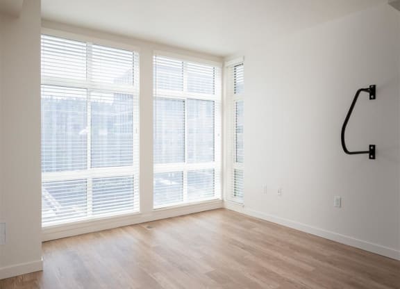 an empty living room with large windows and a wood floor