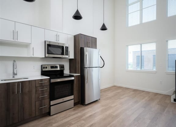 a kitchen with stainless steel appliances and white cabinets and a window