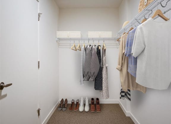 a walk in closet with a rack of clothes and shoes