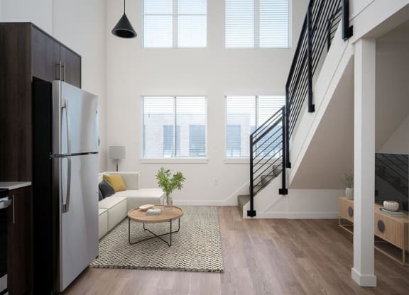 a living room with a refrigerator and a staircase