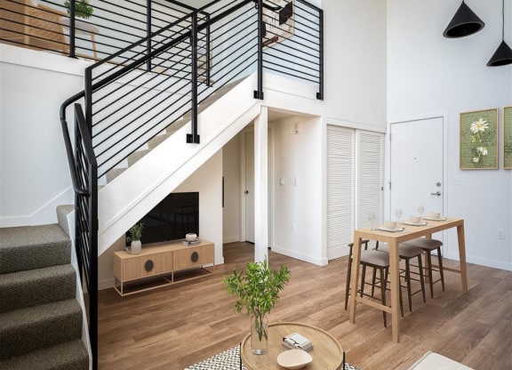 a living room with a staircase and a dining table