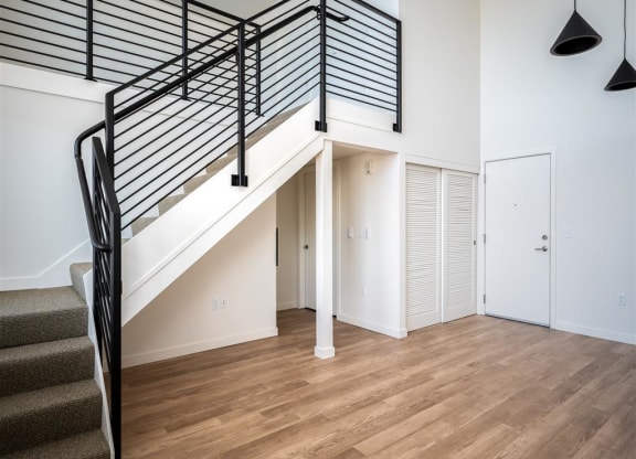 a living room with a staircase in a house with white walls and wood floors