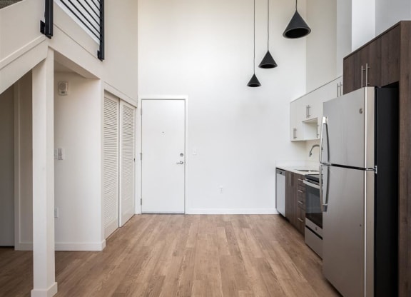 a renovated kitchen with white walls and wood floors and a stainless steel refrigerator
