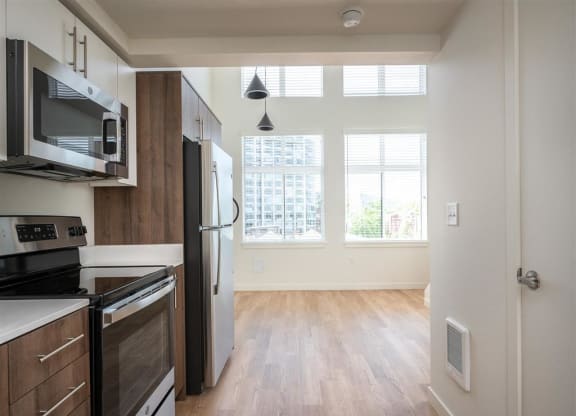 an empty kitchen and living room with a stove refrigerator and microwave