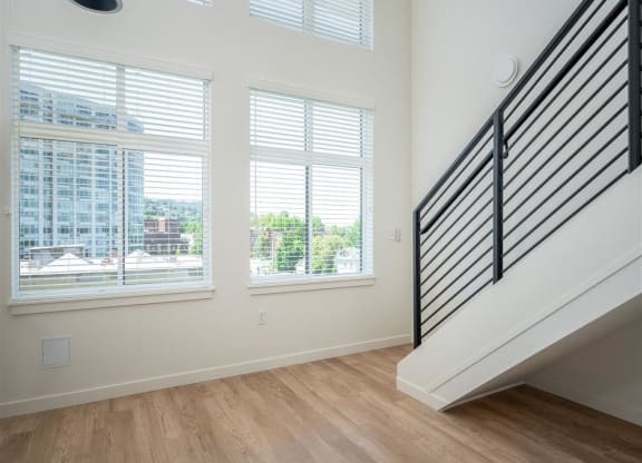 a living room with three windows and a staircase