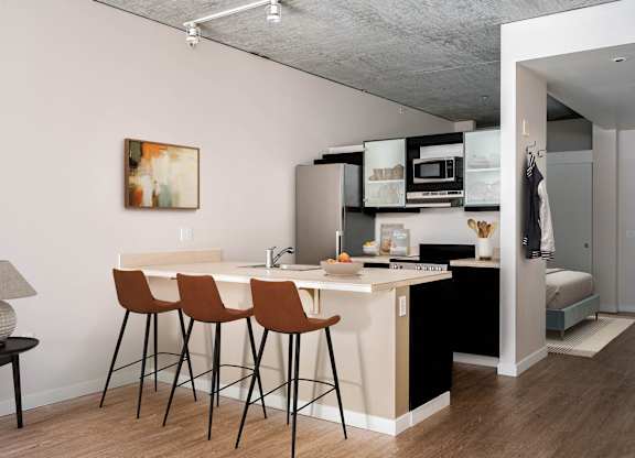 a kitchen and a living room with a bar and stools