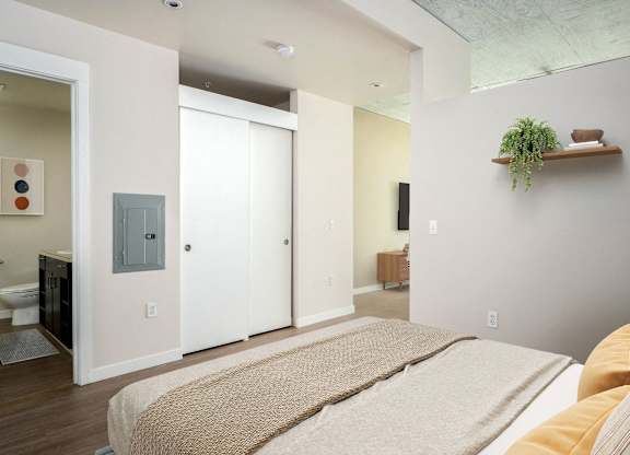 a bedroom with a bed and a bathroom in the background