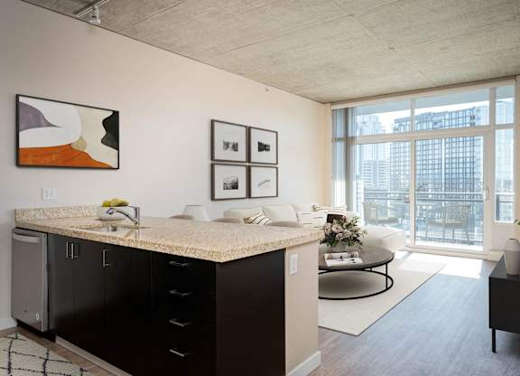 a living room with a large window and a kitchen with a counter top
