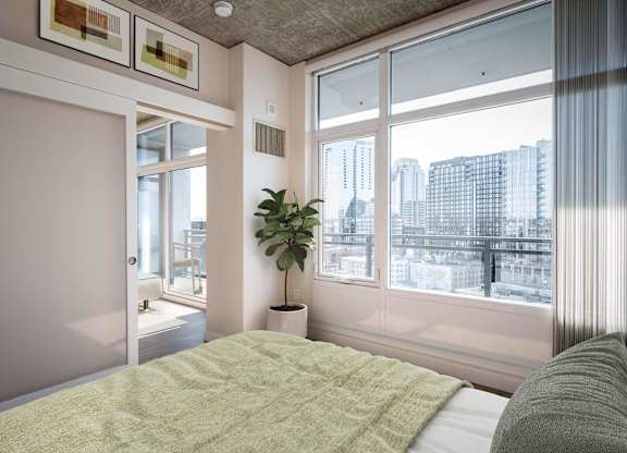 a bedroom with a bed and a large window and a plant