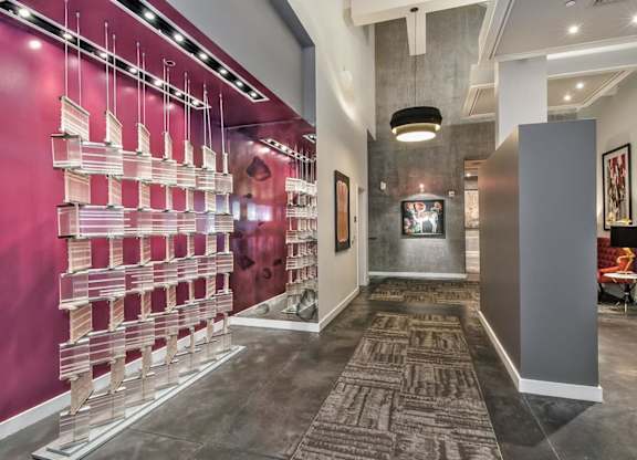 a long hallway with a pink wall and a glass case with pink and white bottles