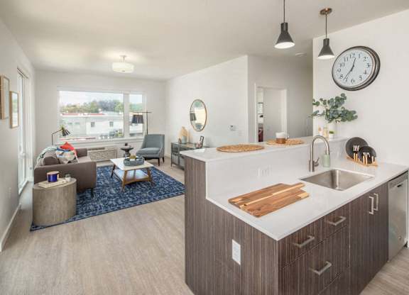 A modern kitchen with a large island and a living room with a couch and a chair.
