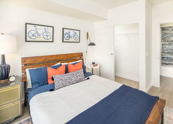 A bedroom with a bed, nightstand, and two bicycle pictures on the wall.