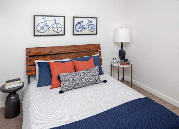 A bed with a wooden headboard and a white comforter with a blue blanket on it.