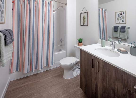 A bathroom with a toilet, sink, and striped shower curtain.