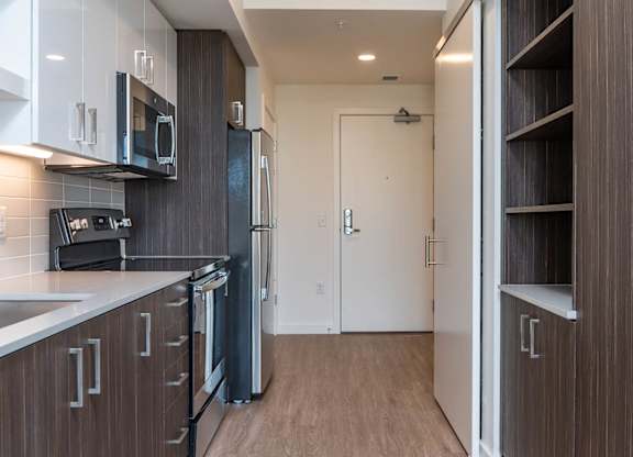 A kitchen with dark wood cabinets and a white counter top.